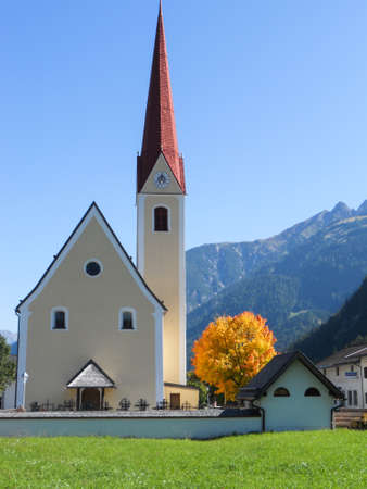 Zell am Ziller, Tyrol, Austria. September 2012. The church of Zell am Ziller with a golden autumn tree, Tyrol, Austria. High quality photoの写真素材
