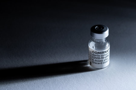 The Netherlands, January 2022. An ampule of vaccine against covid on a grey background with shadow. High quality photo. Close up.のeditorial素材