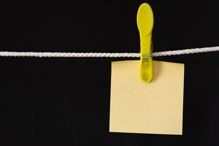 Blank memo papers on rope with peg, on black background. Isolated. High quality photoの写真素材
