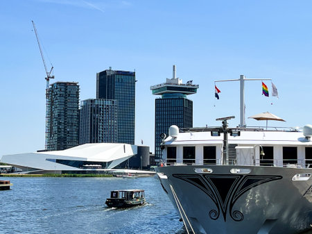 Amsterdam, Netherlands. June 17, 2023. A river cruise boat and the modern architecture of IJdock in Amsterdam. High quality photoのeditorial素材