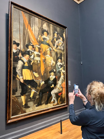 Amsterdam, Netherlands. August 6, 2023. A woman takes a picture of world-famous painting at the Rijksmuseum Amsterdam. High quality photoのeditorial素材
