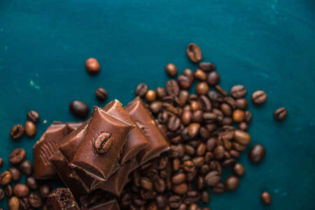 pieces of dark chocolate lie among coffee beans on a dark background top viewの写真素材
