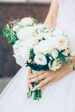 Bride in long sleeve wedding dress holds soft and tender bridal bouquet of rosesの写真素材