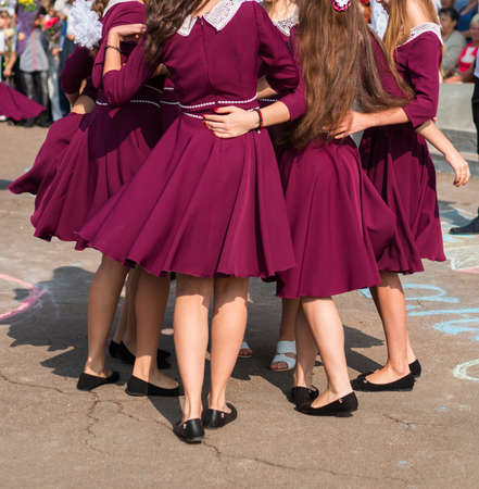 elegant high school graduates in the same dresses of marsala dance a waltz in the schoolyardの写真素材