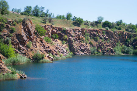 beautiful landscape of a cliff near a reservoir, abandoned quarry, depth, cliff, grass, stones,...
