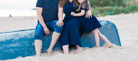 happy family sitting on an inverted boat on the beachの写真素材