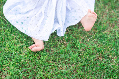 barefoot legs of a child in green grass in the garden. the concept of happy motherhood. summerの写真素材