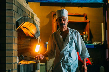 a old man cooks a meat kebab on a grillの写真素材