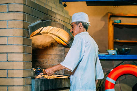 a old man cooks a meat kebab on a grillの写真素材