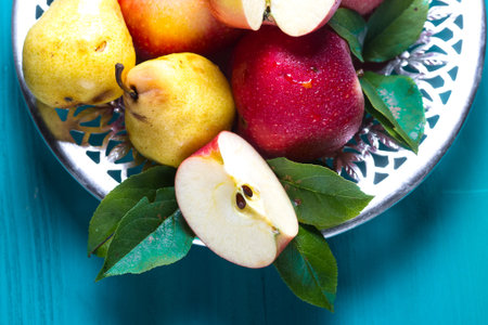 ripe red apples and yellow pears lie in a plate on the table