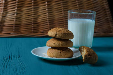 Oatmeal cookies on a plate and cup of milk on a wooden backgroundの写真素材