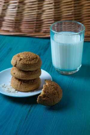 Oatmeal cookies on a plate and cup of milk on a wooden backgroundの写真素材