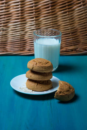Oatmeal cookies on a plate and cup of milk on a wooden backgroundの写真素材