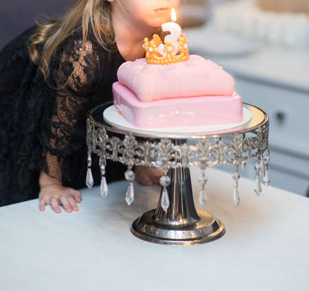birthday little girl blowing a candle on a festive cakeの写真素材