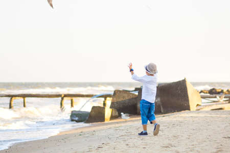 Little boy playing on a pebble beach at sunset. Outdoor recreation. Lifestyle concept.の写真素材