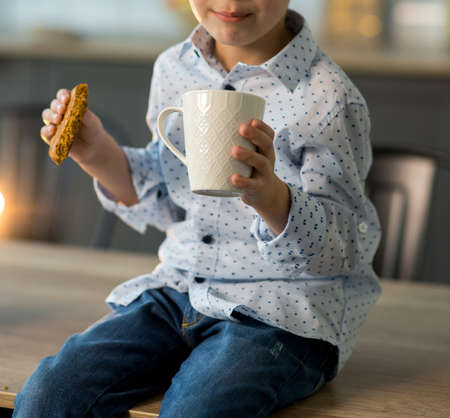 Cute happy boy, eating cookies and drinking milk or tea, waiting for Santa on Christmas Eveの写真素材