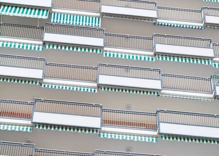 Building with terraces and balconies. Blue and green stripped awnings. Architecture. Background. Pattern.の写真素材