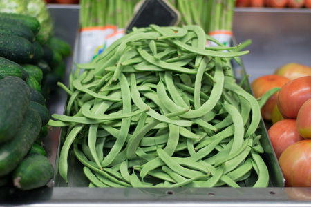 Green beans in the market with cucumbers and tomatoes.