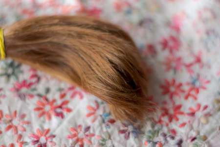 Braid hairstyle. Natural, healthy and red-haired hair on linen fabric with embroidered flowers.の写真素材