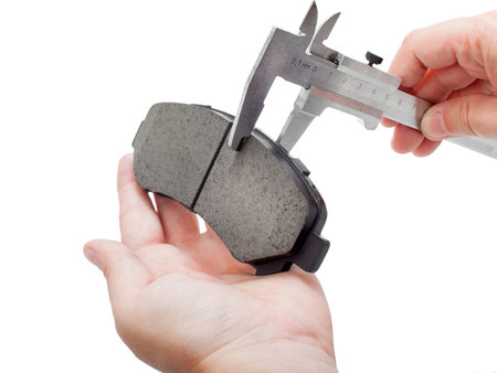 brake pads of the car on a white background, measurement by a caliper of thickness, isolated image...