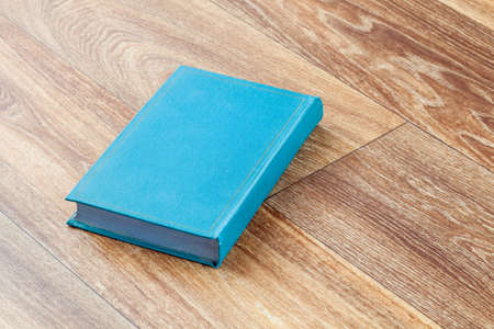 The book blue colour in a firm cover leit on a wooden surface of a table, the top view sideways.の写真素材