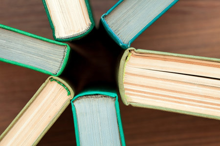 used hardback books or text books seen from above on wooden table.