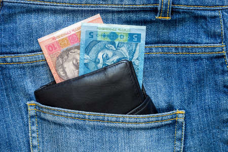 The black leather purse with money looks out of a hip-pocket of jeans.の写真素材