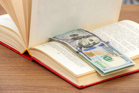 Money in the book, cash between pages of the book on a table.の写真素材
