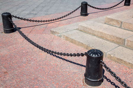 bollard cast-iron black color with chains against the background of paving slabs, nobody.の写真素材