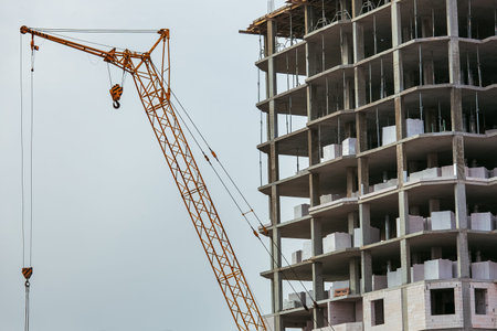 Construction of the building, facade of the building and arrow of the construction crane with a hook...
