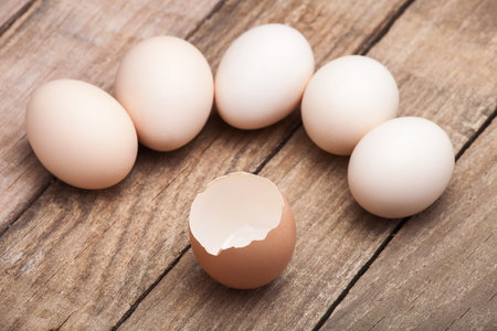 The eggs, the top view which are laid out on a wooden table from old boards with the broken egg in...