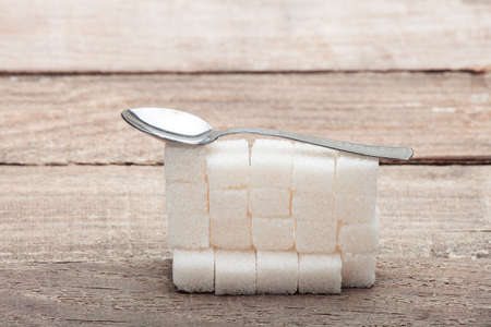 The refined sugar put by a pyramid on a wooden table from old boards, with a teaspoon.の写真素材