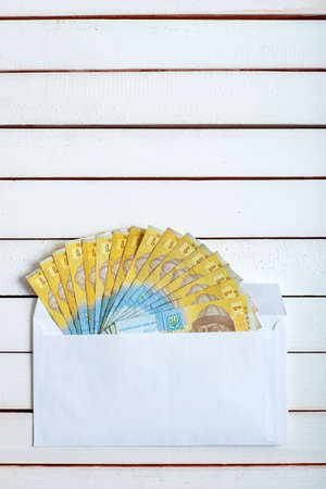 Cash in an envelope, the denomination of ukrainian hryvnia on a table from white wooden boards.の写真素材