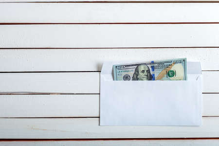 Cash in an envelope, the denomination on a table from white wooden boards.の写真素材