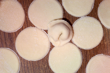 The dough rolled with circles on a wooden kitchen table.