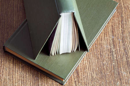 The book in firm cover lies on a table with wooden texture.の写真素材