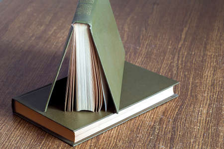 The book in firm cover lies on a table with wooden texture.の写真素材