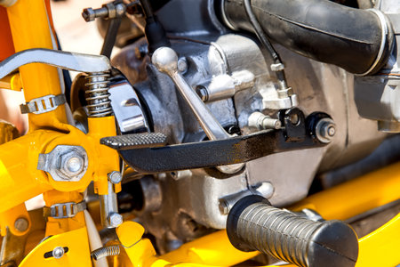 Pedal of a brake of the motorcycle of black color, against the background of the yellow and...