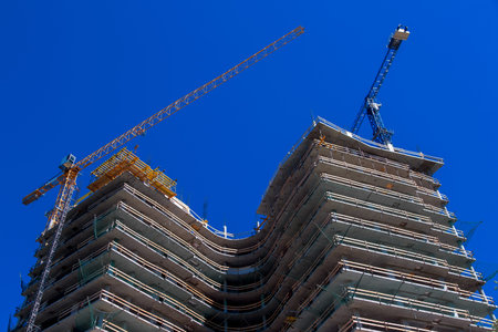 High rise building under construction, seen from below against blue sky.