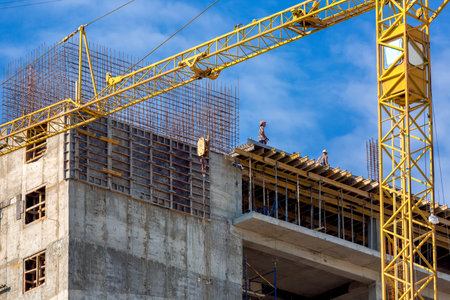 High rise building under construction, seen from below against blue sky.