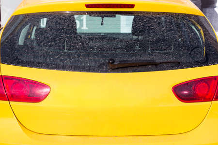 dirty rear glass of the car of yellow color, back view.の写真素材