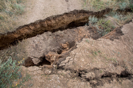 cracks in soil after a landslide in a consequence of an earthquake and undermining of underground...