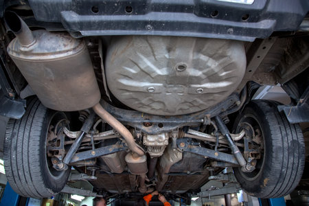 Car undergoing repair or a service in a workshop raised in a car lift.の写真素材