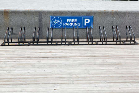 the bicycle parking from metal of black color on a wooden flooring for safe fixing of wheel vehicles, with sign free parking.の写真素材