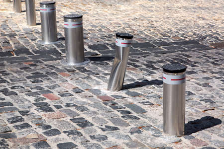 Retractable electric bollard metallic, and hydraulic for the control of road traffic locked up underground, bent from the impact of the car, a damaged mechanism in the wake of the crash.の写真素材