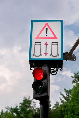 Traffic light with warning sign - Attention automatic retractable electric bollard metallic.