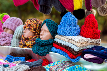 Counter with knitted wool hats and colorful scarves with a mannequin head.