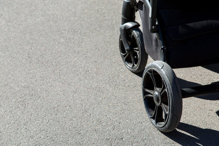 Wheels of a baby carriage close-up on a background of asphalt, wheels go on the road with copy space...