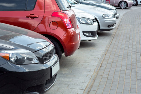 Parked cars in a street parking in a row, close-up of cars standing on the sidewalk of tiles.