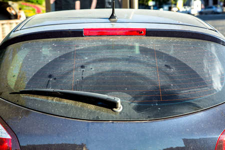 Dirty car rear window, car wagon covered with dust outside in sunny, close-up rear window with car wiper.の素材 [FY310119360897]